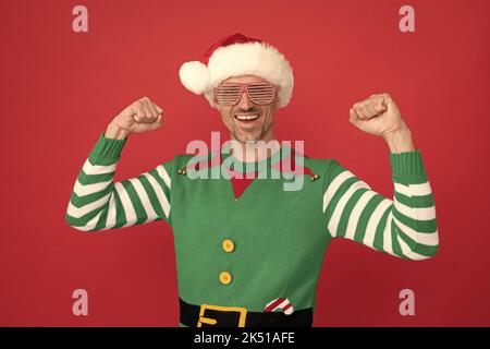 Glücklicher erfolgreicher Mann in Elf Kostüm und Partybrille. weihnachtsmann in weihnachtsmann Hut Stockfoto