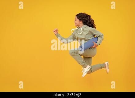 Laufen und springen. Sportbekleidung Werbekonzept. Teenager Kind Mädchen in Trainingsanzügen Jogginganzug posiert im Studio halten Fitness-Matte. Stockfoto