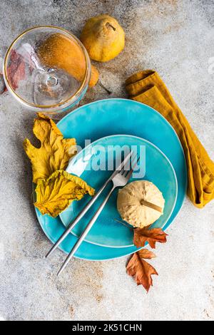 Herbstliches Ambiente mit blauen Keramikgeschirr und saisonaler Dekoration auf einem Betontisch Stockfoto