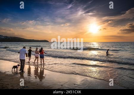 Urlauber genießen einen spektakulären Sonnenuntergang über der Fistral Bay in Newquay in Cornwall in Großbritannien in Europa. Stockfoto