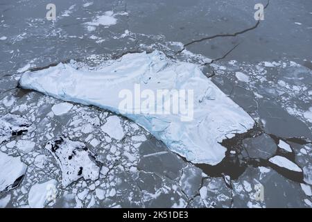 Atemberaubende Drohnenansicht des mit rissem Eis bedeckten Meeres und des Vatnajokull-Gletschers in Island Stockfoto