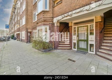 Fassade eines Backsteinwohngebäudes mit Fenster und geschlossener hölzerner Eingangstür auf der Straße in der Stadt Stockfoto