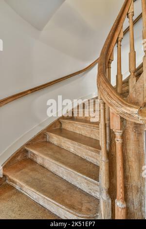 Innenraum eines geräumigen Flurs mit Holztreppe, verziert mit ornamentalen Elementen in Geländern und weißen Wänden Stockfoto