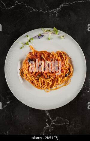 Ansicht von oben von leckeren Spaghetti alla puttanesca Gericht mit Tomatensauce und Meeresfrüchten garniert mit Knoblauch und Chili-Pfeffer und serviert auf Teller in italienischen r Stockfoto