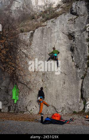 Junger Mann mit Seil klettert auf den Felsen in der Napoleonica, Triest Stockfoto