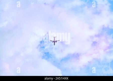 Rotes Passagierflugzeug am blauen Himmel mit rosa Wolken Stockfoto