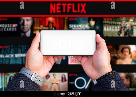 Belgrad, Serbien - 05. Oktober 2022: Smartphone mit leerem Bildschirm in den Händen halten und Netflix-Logo im Hintergrund. Netflix ist TV-Show und Film-Serie Stockfoto