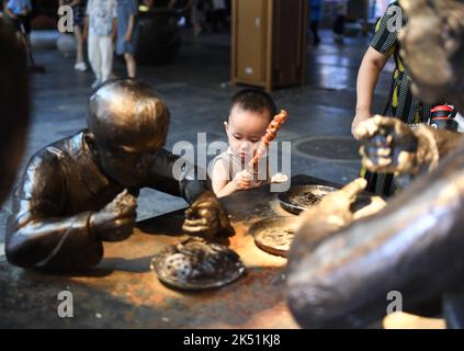 (221005) -- PEKING, 5. Oktober 2022 (Xinhua) -- Ein Kind besucht die Qianmen-Straße, eine wichtige Handelsstraße in Peking, der Hauptstadt Chinas, 16. Juli 2022. Laut der National Cultural Heritage Administration haben die chinesischen Behörden geplant, die Pekinger Zentralachse als Chinas Bewerbungsprojekt für das Weltkulturerbe im Jahr 2024 zu empfehlen.die Pekinger Zentralachse ist 7,8 Kilometer lang, Ausgehend vom Yongding Gate im Süden der Stadt und endend mit dem Drum Tower und dem Glockenturm im Norden. Die meisten der großen Altstadtgebäude von Peking befinden sich entlang dieser Achse. Die Mittelachse ist die Stockfoto