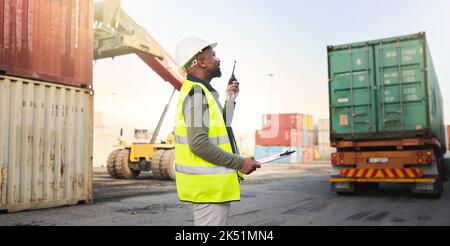 Schwarzer Mann, der in der Transport- und Supply-Chain-Industrie im Reederei-Hafen für Lager-, Logistik- und Frachtzustellung arbeitet. Mitarbeiter mit Radio Stockfoto