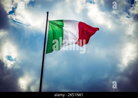Italienische Nationalflagge fliegt gegen launischen Himmel Stockfoto