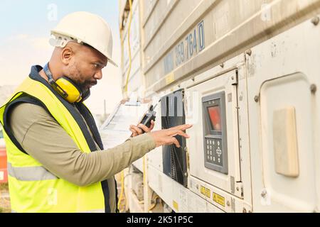 Logistikingenieur, Kühlschrank und Versandbehälter mit Tastatur für Kühlvorschriften. Industriemanager, Führung und schwarzer Mann mit Walkie Stockfoto