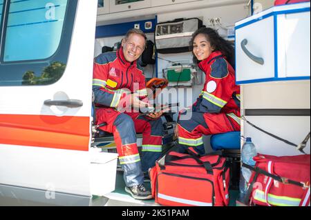 Fröhliche Sanitäter posieren für die Kamera im Krankenwagen Stockfoto