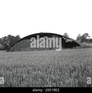 1964, historisch, Heufässer hoch unter einem offenen gewölbten Unterstand auf einem Feld, Stocken Farm, Bucks, England, Großbritannien, Um sie vor widrigen Witterungsbedingungen zu schützen. Stockfoto