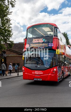 Ein rot geöffneter, Hop-on-Hop-off-Tourbus fährt durch das Zentrum von Cambridge, Großbritannien. Stockfoto