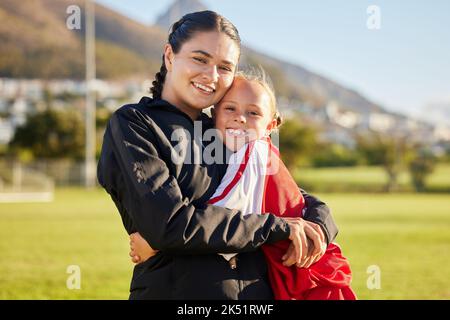 Fußballtrainer, Kind und Umarmung während des Sporttrainings auf dem Fußballplatz für Fußball und zeigen dabei Unterstützung und Motivation für das Spiel. Porträt von Mädchen Kind Stockfoto