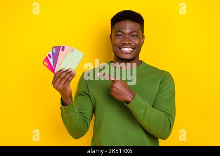 Portrait von gutaussehenden trendigen fröhlichen Kerl Urlaub demonstriert mobile Fälle auf hellgelben Hintergrund isoliert Stockfoto