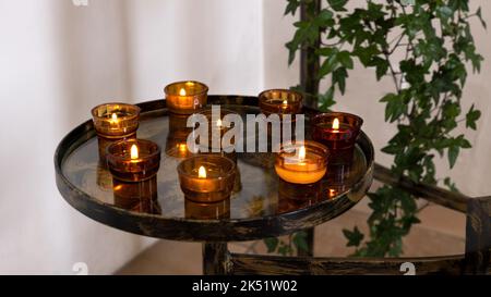 Brennende Votivkerzen in Glasschalen auf einem runden Tablett Stockfoto