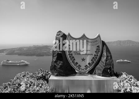 Fira, Santorini - September 4, 2022 :das Label eines berühmten Champagner, ein Kreuzfahrt-Schiff und der Vulkan von Santorini Griechenland in schwarz und weiß Stockfoto