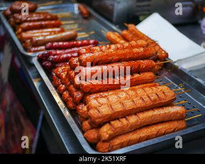 Nahaufnahme von gegrillten Würstchen auf dem Tablett und Verkauf auf dem Nachtmarkt. Stockfoto