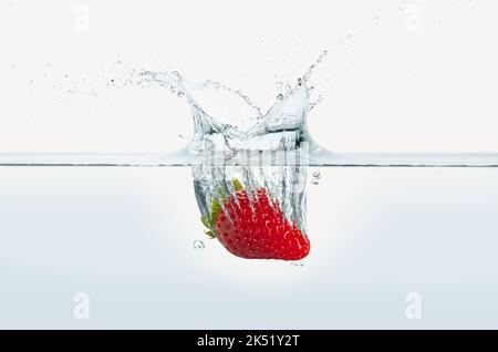Erdbeere spritzt in Wasser. Seitenansicht auf weißem Hintergrund. Stockfoto