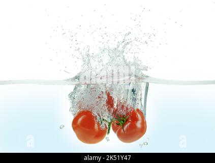 Drei Tomaten, die in Wasser spritzt. Seitenansicht auf weißem Hintergrund. Stockfoto