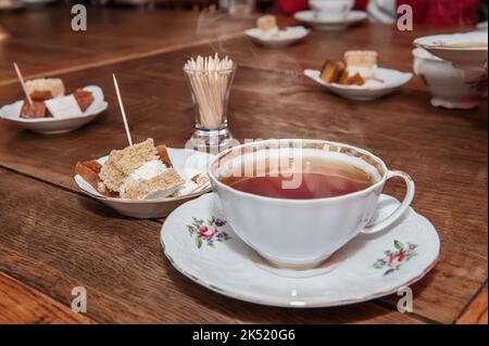 Porzellanbecher mit Tee und natürlicher Apfelpastillle auf einem Holztisch in einem Café Stockfoto