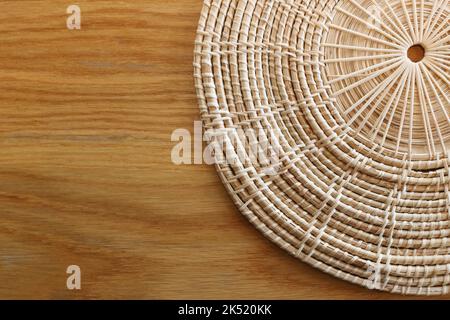 Korbwaren aus runder Rattan zum Servieren von Geschirr auf dem braunen Holztisch. Stockfoto