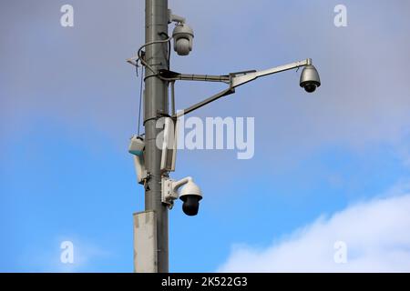 Überwachungskameras für den Außenbereich an einem Straßenmast in blauem Himmel. CCTV-Kamera, Konzept für Sicherheit, Privatsphäre und Schutz vor Kriminalität Stockfoto