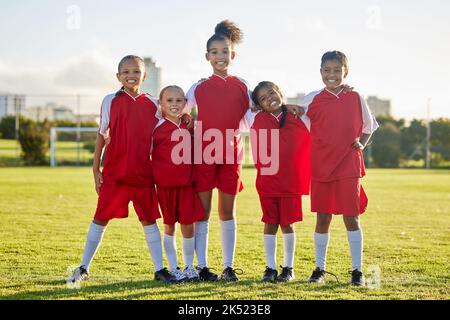 Mädchenmannschaft, Kinder auf dem Fußballplatz und Sportentwicklung für glückliche Mädchen im Gruppenportrait zusammen. Teamwork, Fußball und stolze weibliche Kinder aus Stockfoto