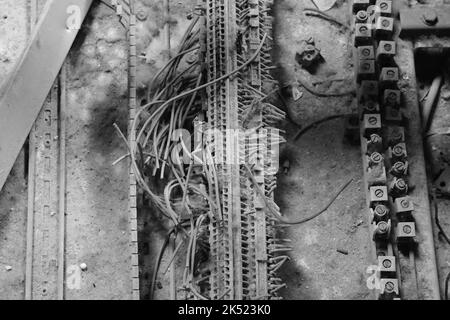 Eine Graustufenaufnahme von schmutzigen, alten und staubigen elektrischen Netzwerkkabeln auf einem Boden Stockfoto