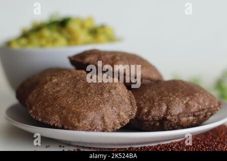 Ragi Poori serviert mit gewürzten Kartoffelpüree als Beilage. Frittiertes indisches Fladenbrot aus Fingerhirse und Weizenmehl ist eine interessante Art und Weise o Stockfoto
