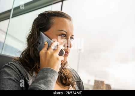 Junge Frau, die in einem öffentlichen Raum telefoniert Stockfoto