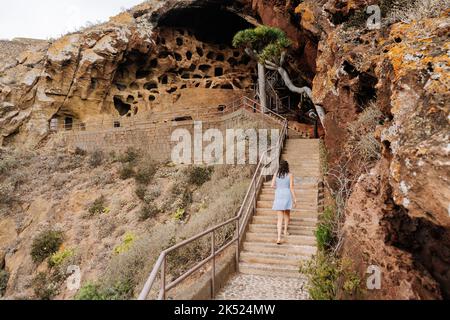 Frau, die eine Treppe zu einer vulkanischen Höhle auf Gran Canaria klettert Stockfoto