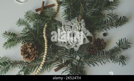 Makramé Schneeflocke Weihnachten Feiertagsdekoration auf Ästen mit Makrame handgefertigten Knot-Technik Stockfoto