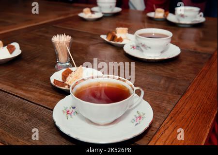 Porzellanbecher mit Tee und natürlicher Apfelpastillle auf einem Holztisch in einem Café Stockfoto