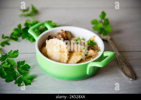 Kartoffelknödel mit Zwiebel und Pilzen in einer Keramikplatte. Stockfoto