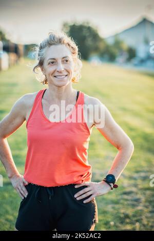 Echte junge reife kaukasische Frau in einer Sportkleidung im Park an einem sonnigen Nachmittag. Stockfoto