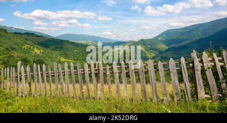 Ländliche Berglandschaft im Sommer. Urlaub in der karpatischen Landschaft. Wiesen und Wälder auf sanften Hügeln unter einem blauen Himmel mit flauschigen Klo Stockfoto