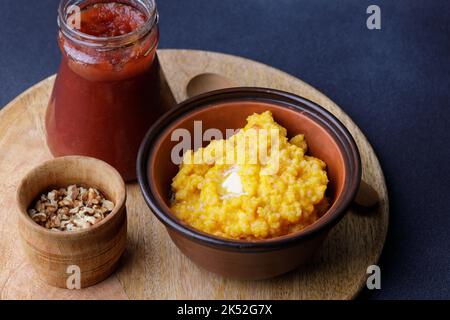 Süßer Kürbisbrei in Tonschüssel mit Marmelade und Nüssen Stockfoto