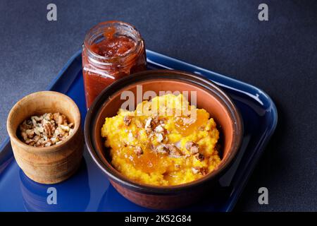 Süßer Kürbisbrei in Tonschüssel mit Marmelade und Nüssen Stockfoto