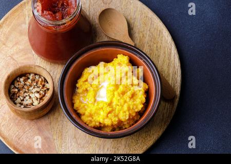 Süßer Kürbisbrei in Tonschüssel mit Marmelade und Nüssen Stockfoto