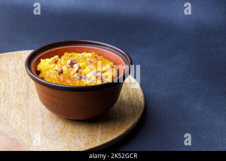 Süßer Kürbisbrei in Tonschüssel mit Marmelade und Nüssen Stockfoto