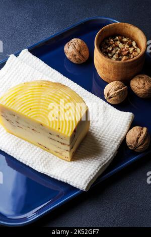 Ein Stück Käse mit Walnüssen auf dem blauen Tablett serviert Stockfoto