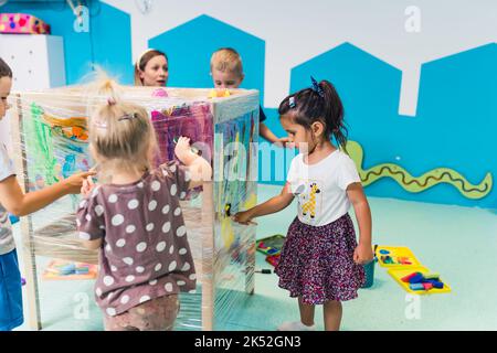 Vorschulkinder haben Spaß mit ihrer Lehrerin und Malerei, Kindergarten. Hochwertige Fotos Stockfoto