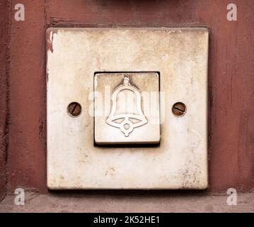 Einfache alte Türklingel, rechteckiger Türglockenschalter mit Glockensymbol darauf, Objekt-Makro, extreme Nahaufnahme, Vorderansicht, Frontalaufnahme, Niemand, keine Menschen. Stockfoto