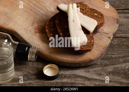 Ein Stück Brot mit Speck ein Glas Wodka auf dem Tisch, alkoholische Getränke und ein Snack, schlechte Gewohnheiten, Alkoholabhängigkeit, Essen und Getränke Stockfoto