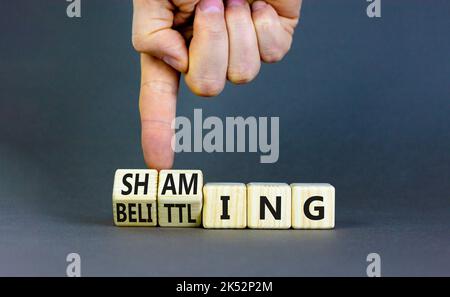 Schämendes und herabsetzendes Symbol. Konzeptwörter, die auf Holzwürfeln schämen und herabwürfeln. Geschäftsmann Hand. Schöne graue Tabelle grauen Hintergrund. Unternehmen Stockfoto