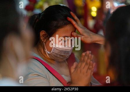 5. Oktober 2022: Eine Frau betet, während sie während des Hinduurlaubs Vijaya Dashami in Bangkok, Thailand, das heilige Vibhuti-Pulver auf ihre Stirn reiben lässt. Das Hindu-Ereignis wird von vielen Menschen in der buddhistischen Mehrheitsnation beobachtet. Tausende von Menschen drängten sich in den belebten Straßen des Geschäftsviertels Silom, wo sich der Sri Maha Mariamman-Tempel, das größte Hindu-Gotteshaus in Thailand, befindet. (Bild: © Adryel Talamantes/ZUMA Press Wire) Stockfoto