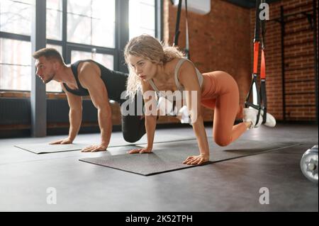 Junges Paar, das sich beim Training im Fitnessstudio die Beine streckt Stockfoto