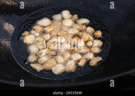 Große Stücke von rohem Lamm Fett Schwanz dumba in Öl gebraten mit Blasen in einem schwarzen Kessel Nahaufnahme Kochen Lebensmittel Stockfoto